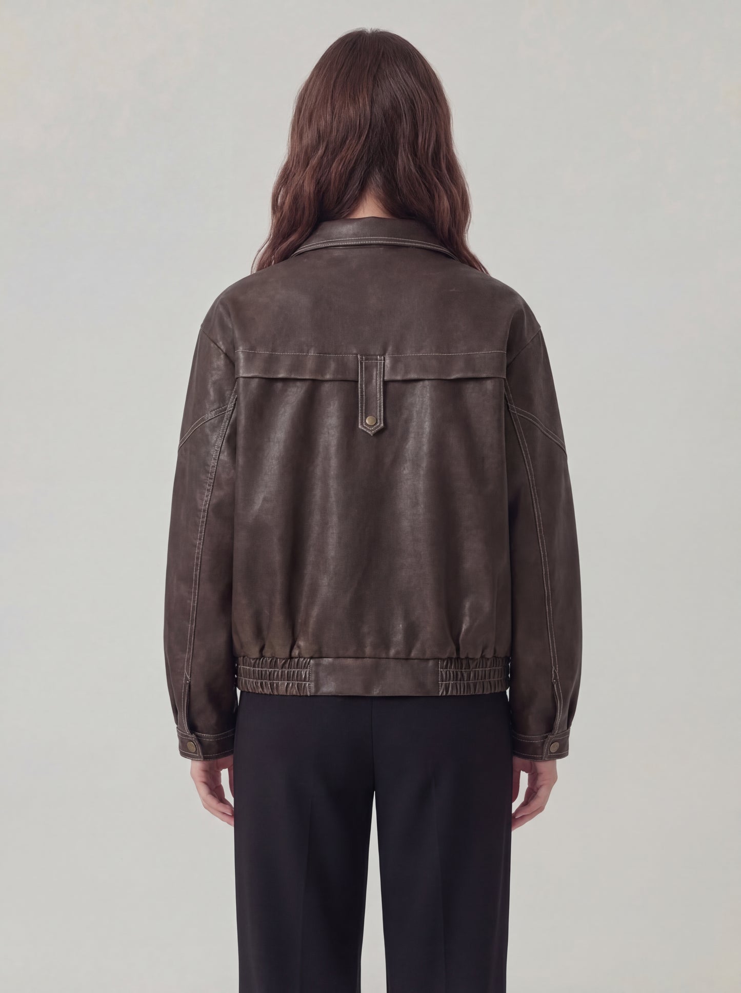Person wearing a brown leather jacket on a plain background