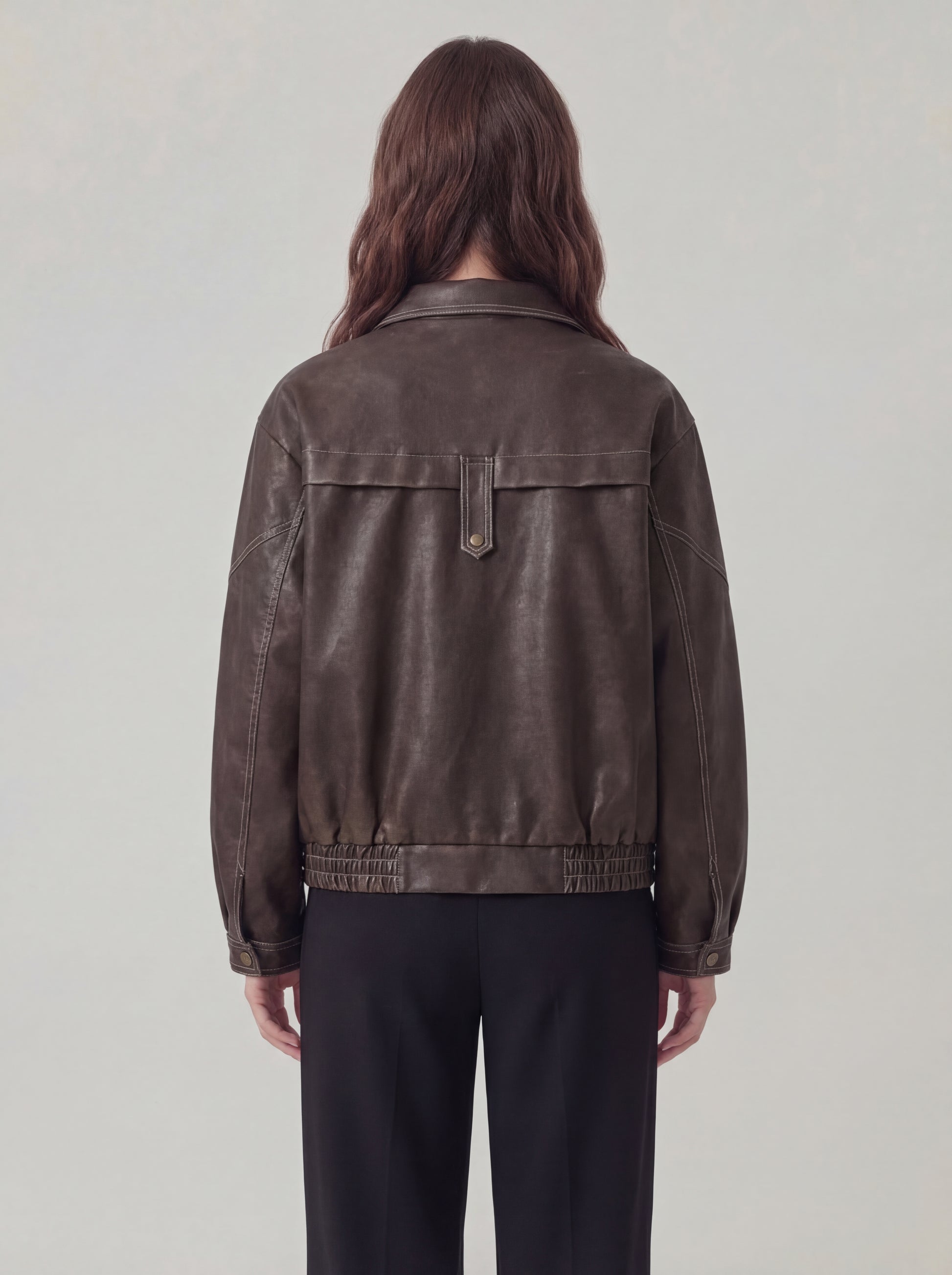 Person wearing a brown leather jacket on a plain background