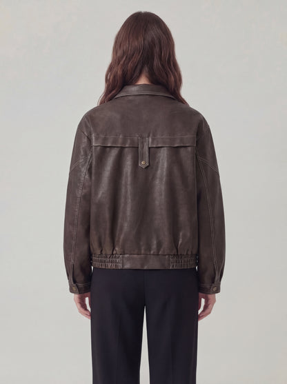 Person wearing a brown leather jacket on a plain background