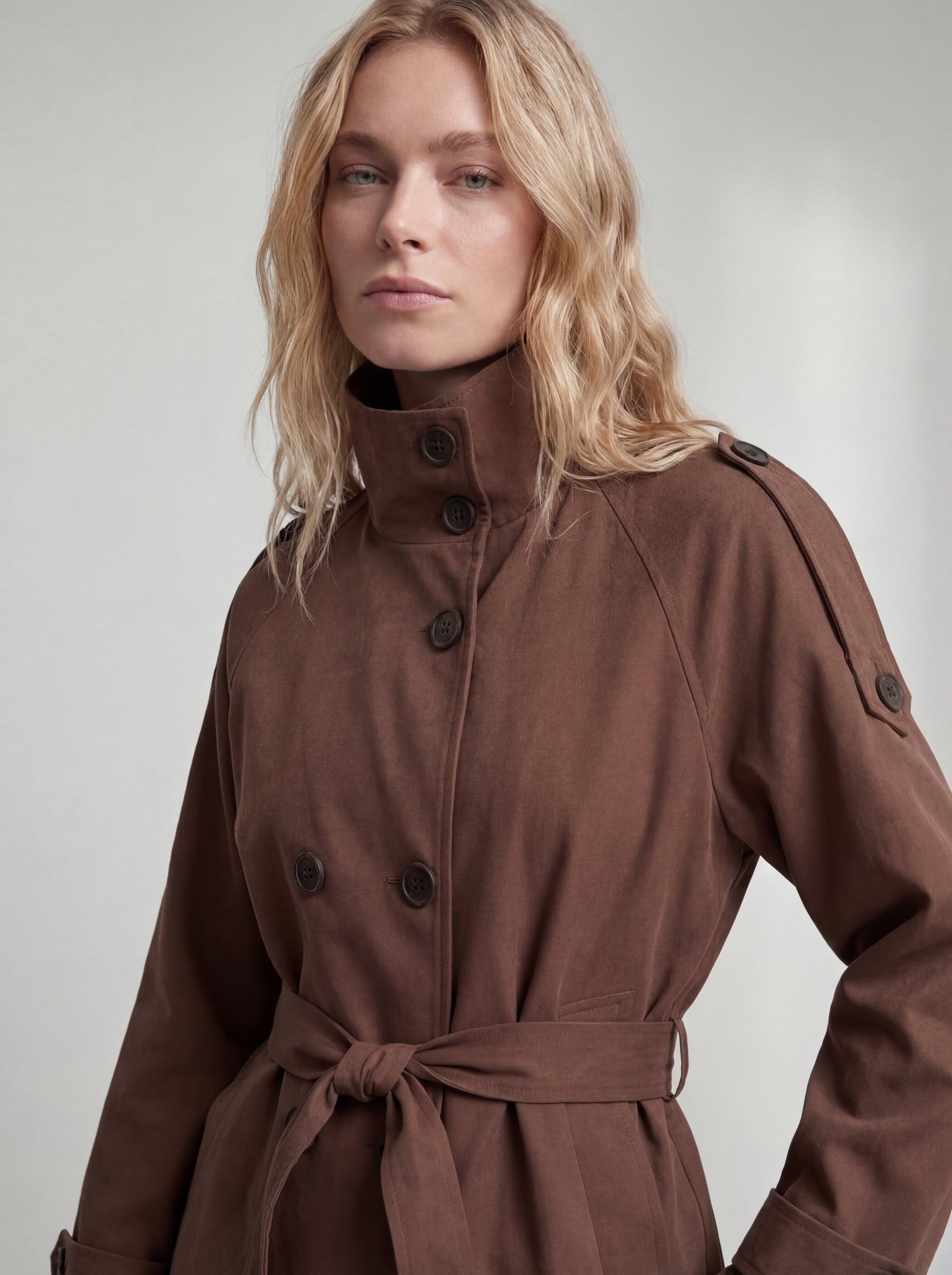 Woman wearing a brown coat against a plain background