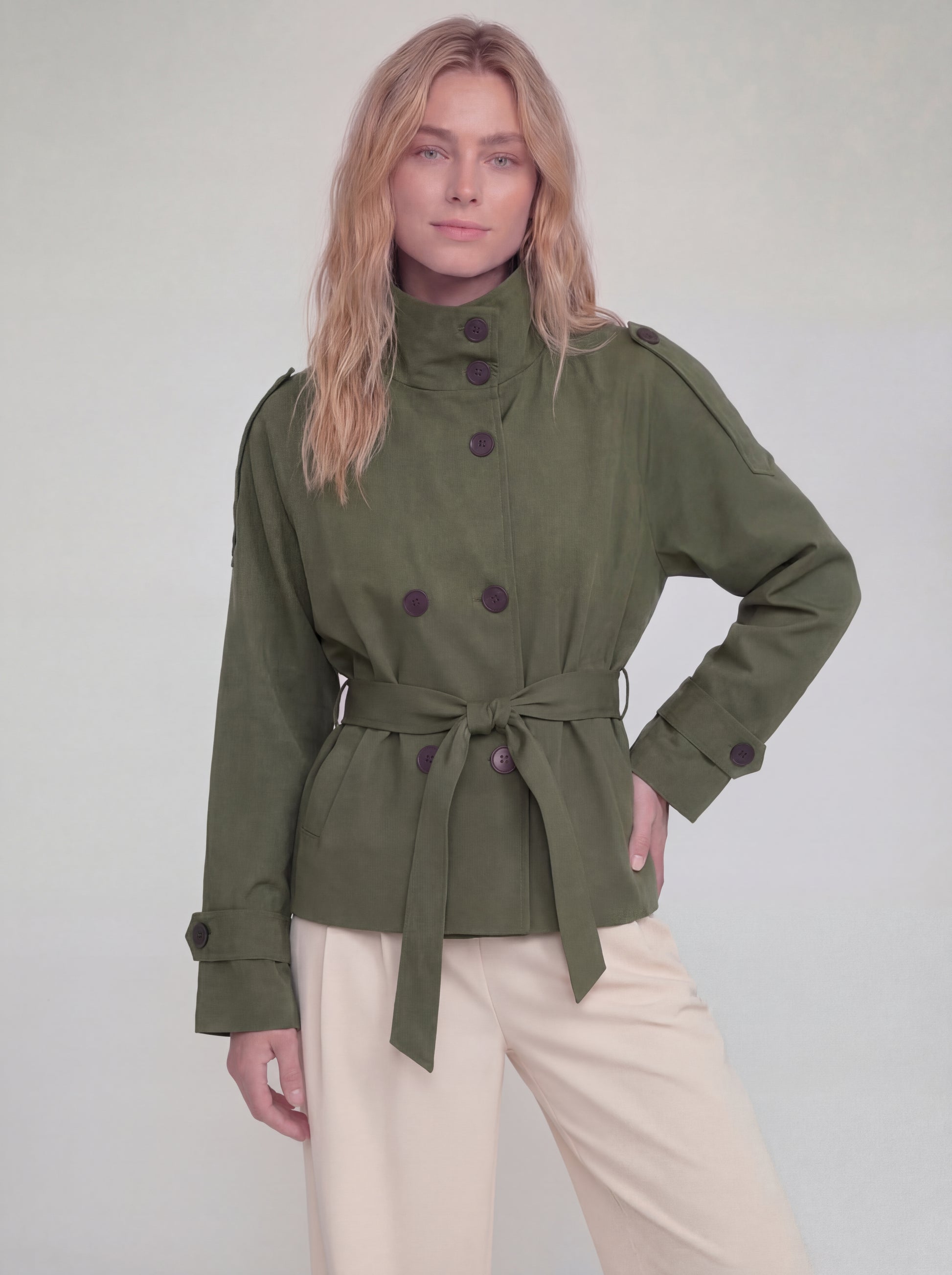 Woman wearing a green jacket with buttons on a plain background