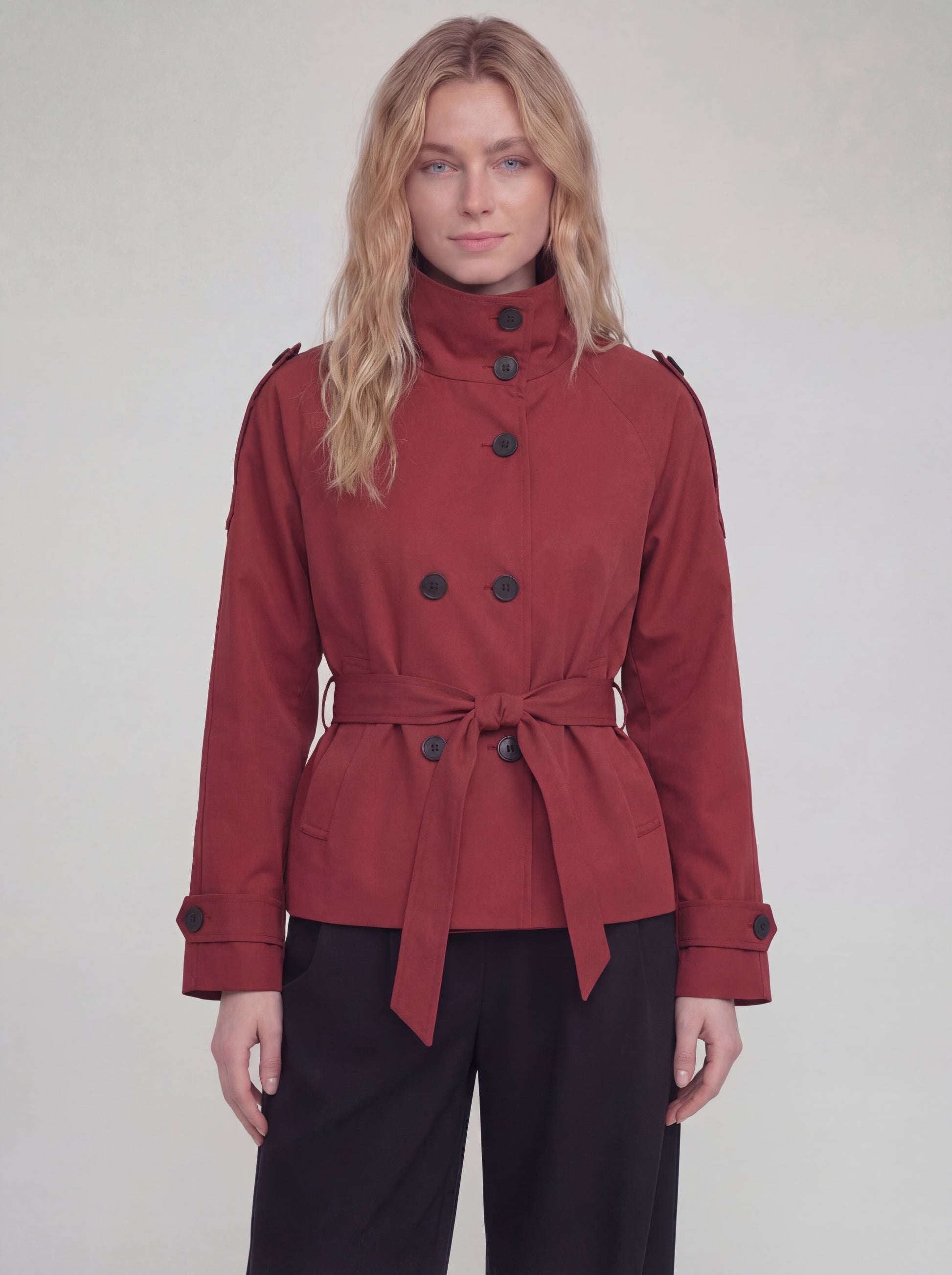 Woman wearing a red coat with black buttons on a plain background