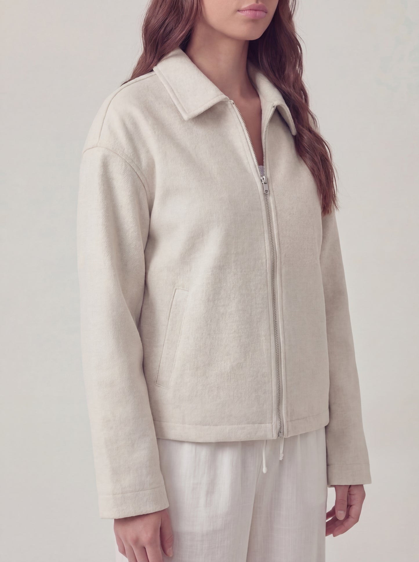 Person wearing a beige jacket on a plain background