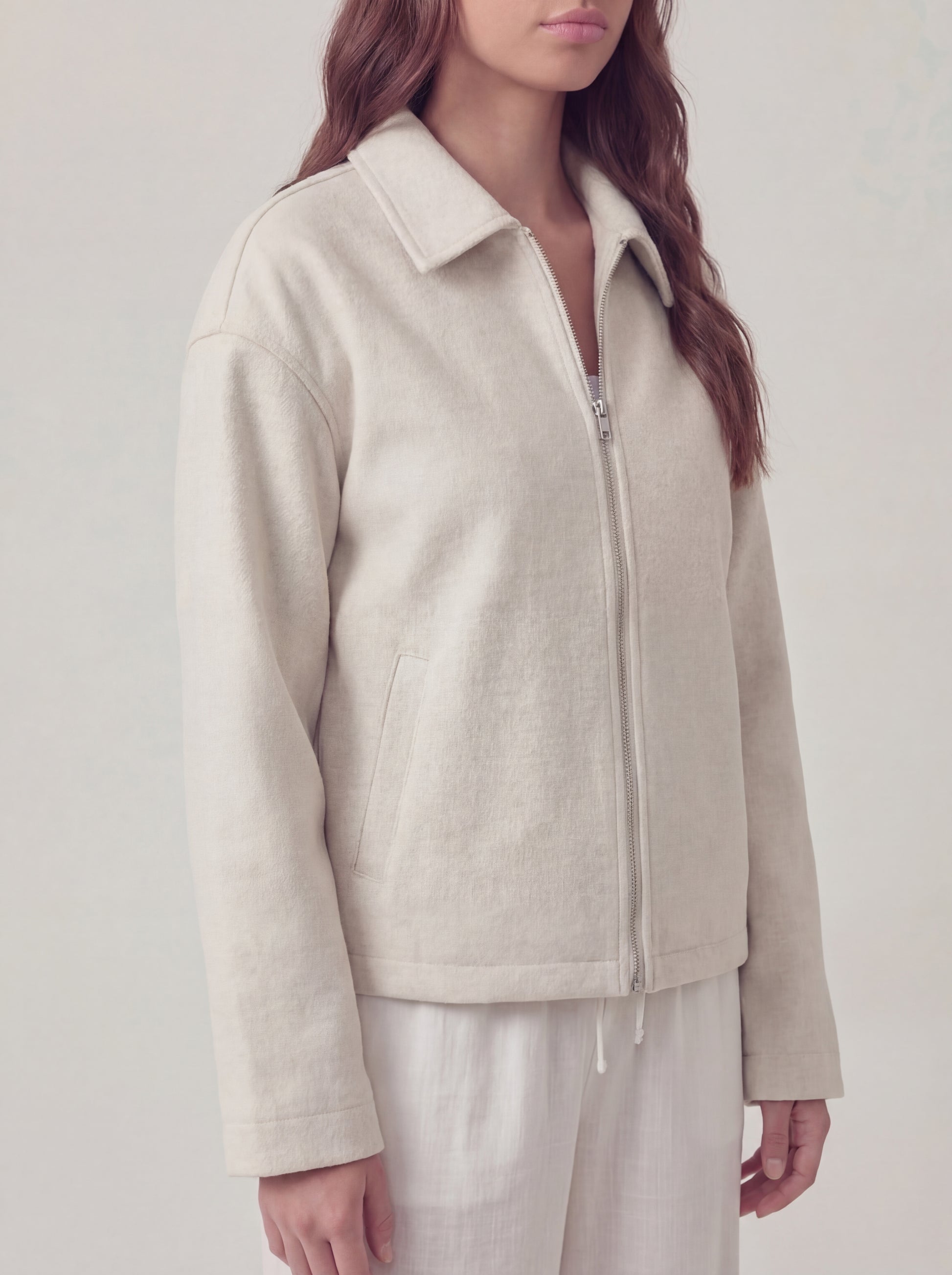 Person wearing a beige jacket on a plain background