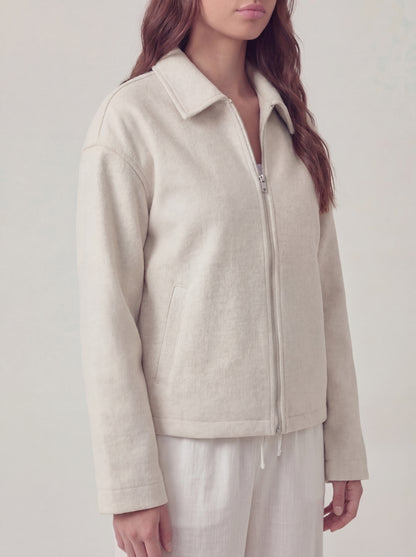 Person wearing a beige jacket on a plain background