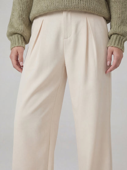 Beige pants worn with a green sweater on a plain background