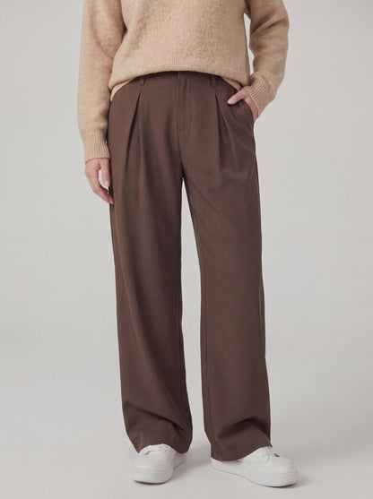 Person wearing brown wide-leg pants and a beige sweater on a plain background