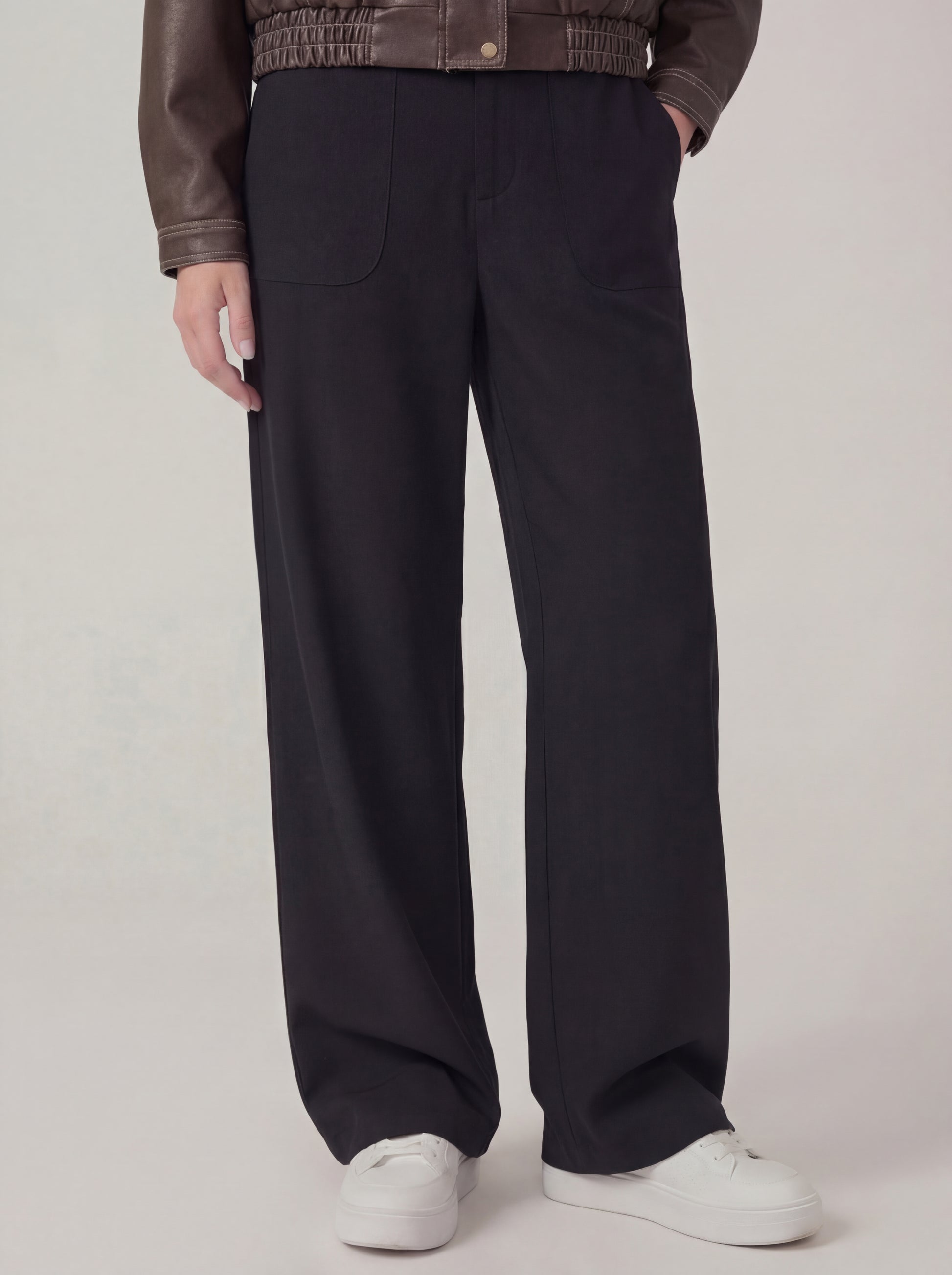 Person wearing black wide-leg pants with a plain background