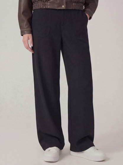 Person wearing black wide-leg pants with a plain background